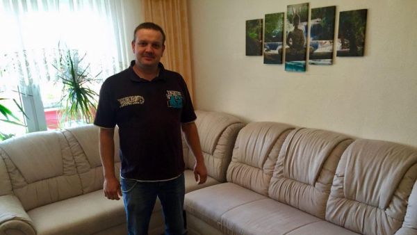 Unser zufriedener Kunde Herr Klugist vor seiner frisch gereinigten Couch und Teppich