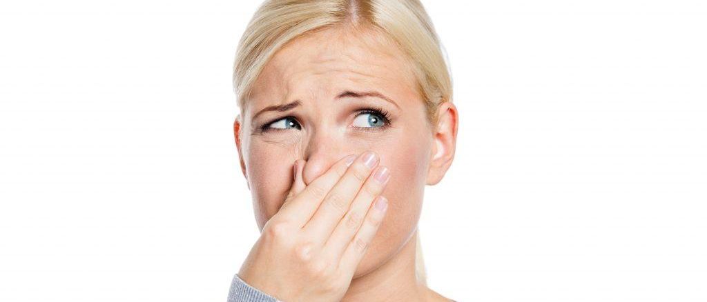 Frau drückt sich aufgrund schlechter Gerüche die Nase zu